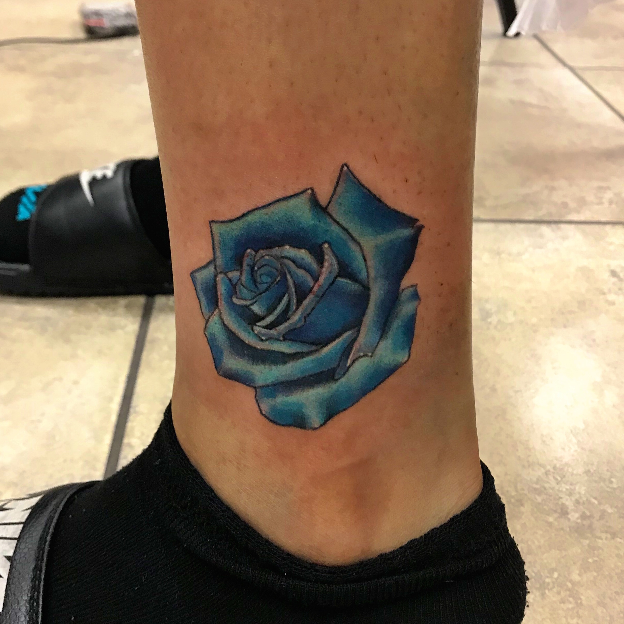 Blue rose tattoo on the inner forearm.