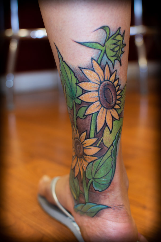 Sunflower design on Calf by Spiro at Artistic Impressions Tattoo Studio located in Katy, Texas