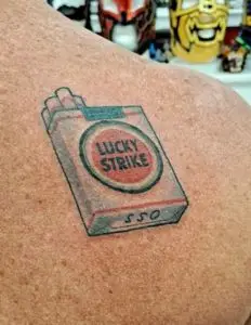 a tattoo of a pack of Lucky Strike cigarettes by Mike at Artistic Impressions Tattoo Studio in Katy, Texas