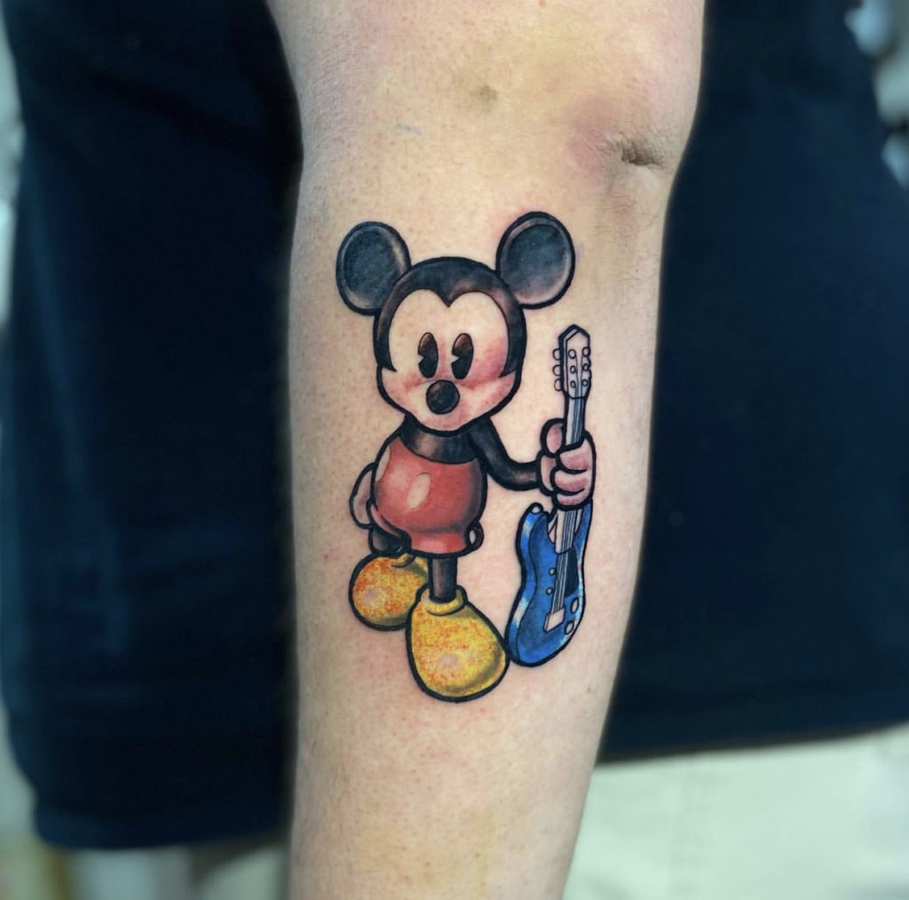 Walt Disney's Mickey Mouse tattoo holding a guitar by Nick at Artistic Impressions Tattoo Studio in Katy,Texas