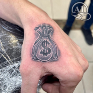 a tattoo of a moneybag on the hand by Biggie at Artistic Impressions Tattoo Studio in Cypress, Texas