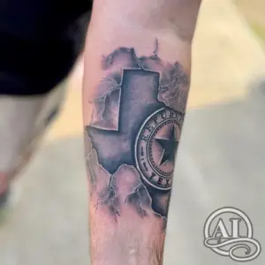 a black and grey tattoo of Texas with a symbol inside by Colton at Artistic Impressions Tattoo Studio
