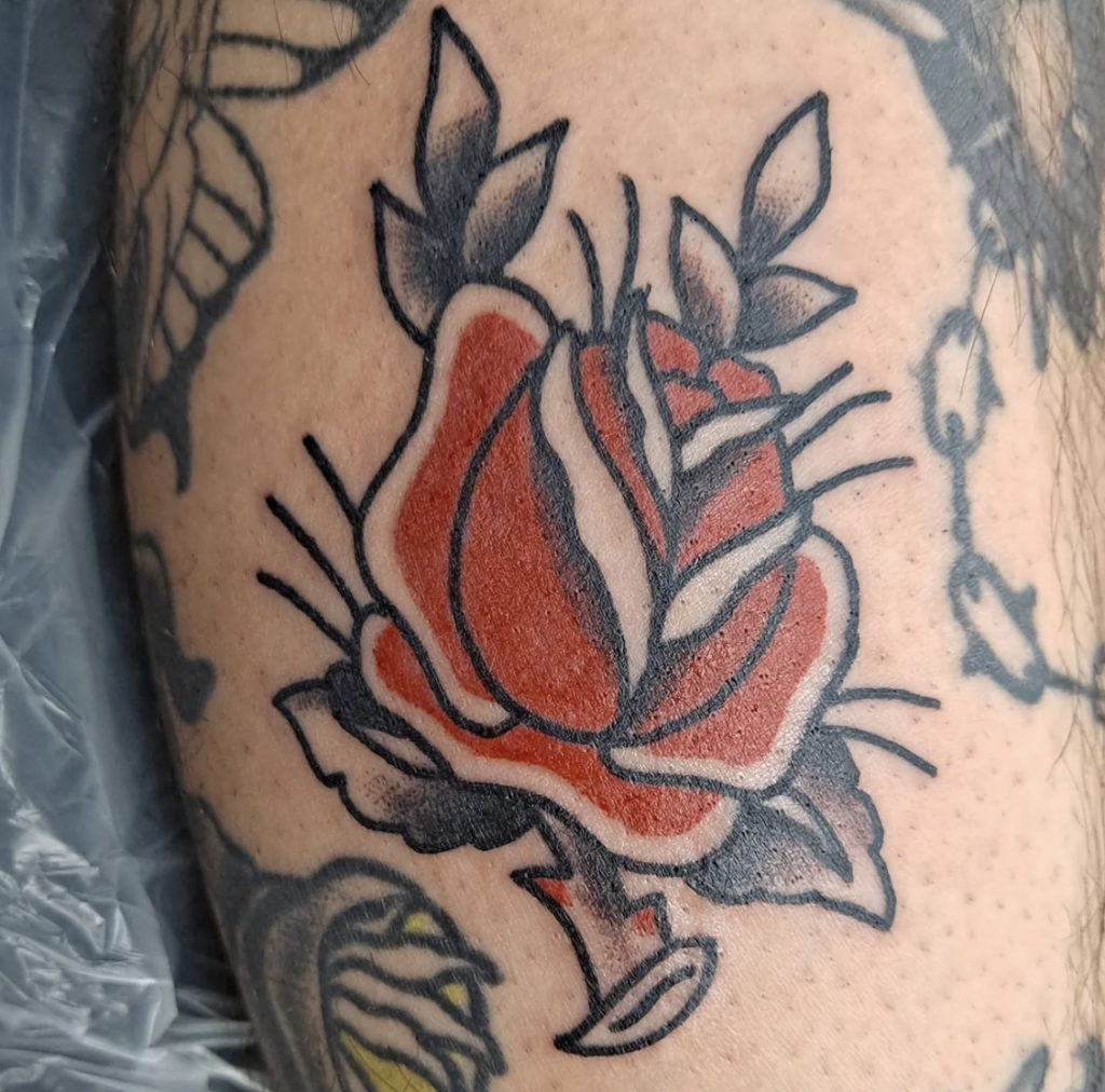 a traditional rose tattoo in black and red by Mike Valadez at Artistic Impressions Tattoo Studio in Katy, Texas