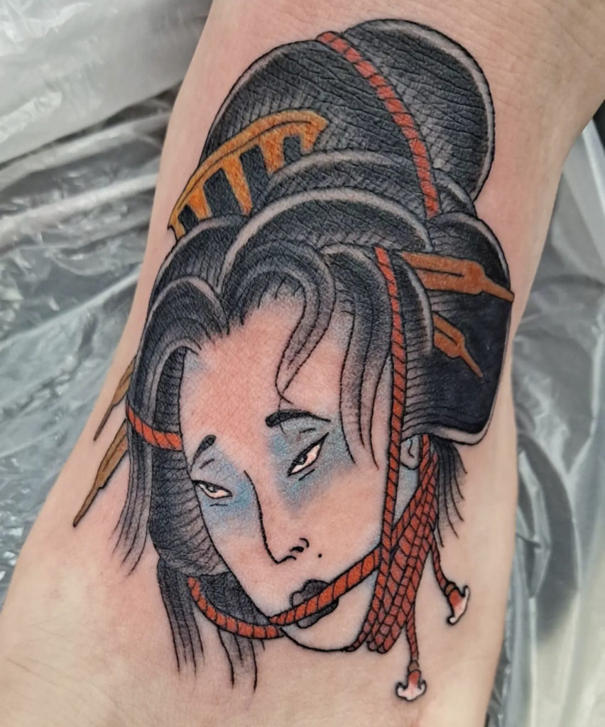 a tattoo of a Japanese Geisha head with rope by Mike Valadez at Artistic Impressions Tattoo Studio in Katy, Texas