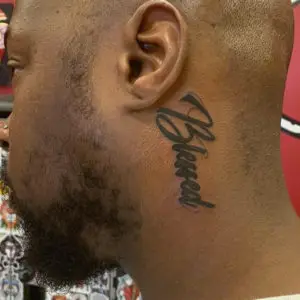 a tattoo of the word "blessed", on the neck by Ulisses at Artistic Impressions Tattoo Studio in Katy, Texas