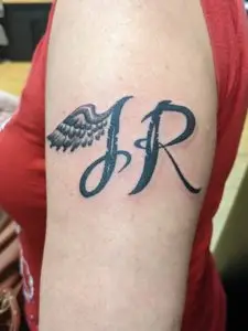 a tattoo of initials with a wing