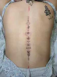 small symbols tattoos lined up vertically on the spine